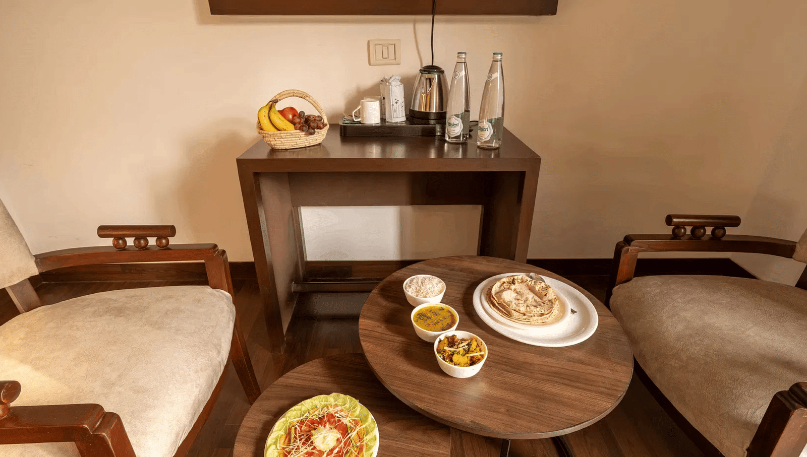 A dining setup with multiple Indian dishes placed on a round table with two chairs - Lime Boutique Bed & Breakfast | Nehru Place Metro